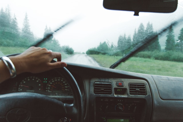 A man driving in the rain with his windshield wipers on
